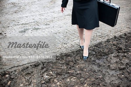 femme d'affaires marcher dans la boue ferme