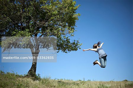 Woman jumping by tree