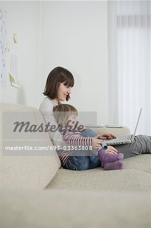 Mutter und Tochter mit Laptop im Wohnzimmer