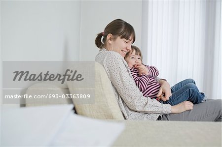 Mutter und Tochter kuscheln auf sofa