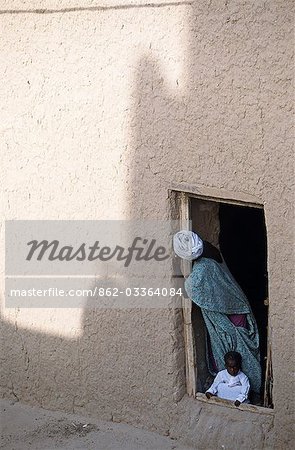 Woman and baby looking out of plain doorway in mud brick house in the old quarter of Timbuktu