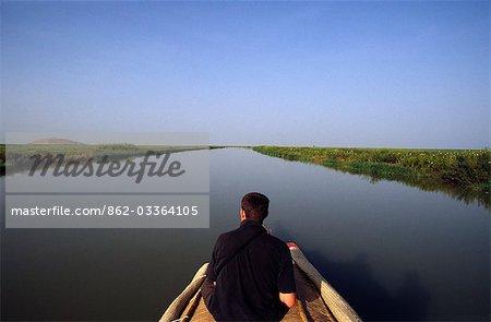 A tourist sits atop a pinasse (motorised riverboat) as it makes it way along the Niger River between Mopti and the port of Korioume at Timbuktu