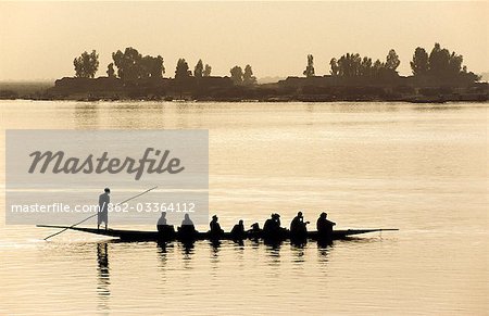 A pirogue loaded with passengers is poled along the Niger River near Mopti. The slender wooden canoes are the traditional craft for fishing and transporting passengers and livestock on the Niger.