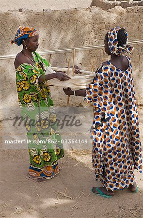 Mali, Senossa. Zwei Peul Frauen bereiten die Stränge der Baumwoll-Garn aus der langen Längen, die sie, um die Wände ihres Hauses gesponnen hatte. Mali ist Afrika der zweitgrößte Baumwolle.