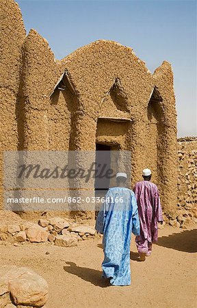 Mali,Gao,Hombori. Two men pass by the imam's house at Hombori which is a traditional mud-brick structure in the Sudanese style of architecture.