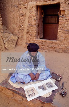 The Librarian sits outside,infront of Mauritania's oldest library,and inspects some old manuscripts.