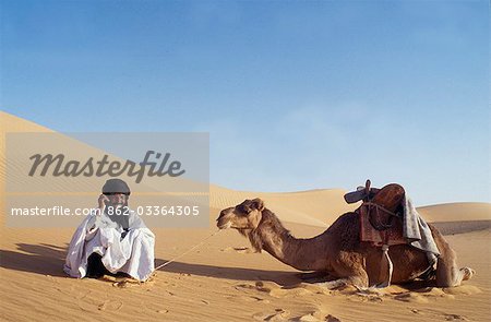A nomad sits in the desert and talks on his mobile phone. It should be noted that it is not always possible to recieve a signal.