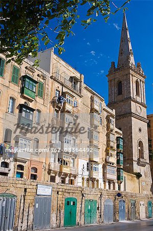 Malta,Valletta. A church spire rises up above closely packed apartments and garages built into the old walls of the city.