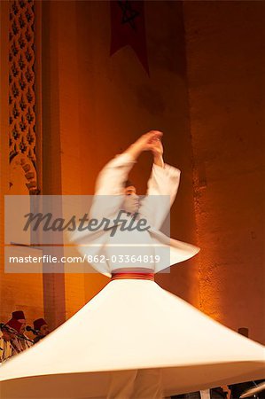 Morocco,Fes. A whirling Dervishe performs on the stage at the Bab Makina during a concert at the Fes Festival of World Sacred Music. Members of the Al Kindi Ensemble perform the music.