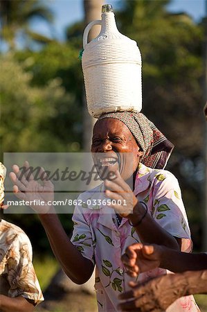 Mosambik, Inhaca Island. Eine afrikanische Dame auf der Insel Inhaca in Mocambique lacht während des Tragens eines Krug hausgemachten Wein.