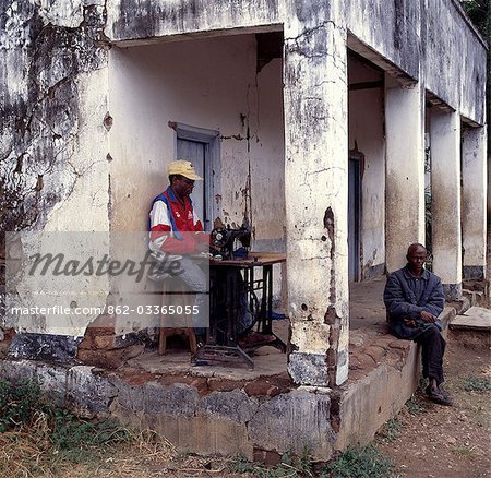 A tailor works on the verandah of his dilapidated shop at Nkhotakota. Lying on the shores of Lake Malawi,Nkhotakota was reputed to have been a centre of the slave trade during the 19th century. Since its heyday,the town has gradually slipped into oblivion. .