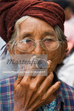 Myanmar. Burma. Nyaung U. Eine alte bespectacled Frau raucht eine lokale Cheroot in Nyaung U-Markt.