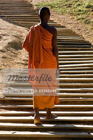 Myanmar,Burma,Loi pan. A monk in saffron robes walks up a long flight of wooden steps towards the 15th or 16th century Wan-seeing monastery.