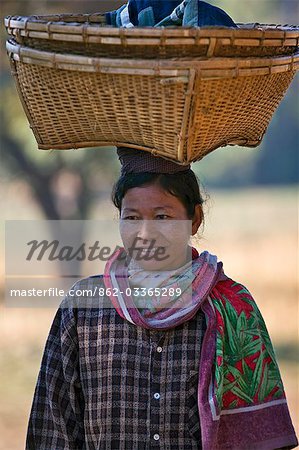 Myanmar, Birmanie, Mrauk U. Une femme de Rakhine retourne du marché de Mrauk U avec un panier en bambou tissé sur sa tête.