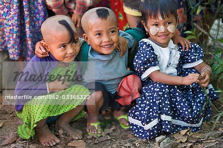 Myanmar,Burma,Rakhine State,Gyi Dawma. Three young friends at Gyi Dawma village. The small tufts of hair on the shaven heads of two of them are believed to protect them.