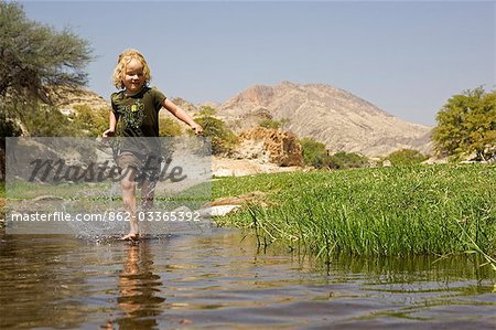 Région de Namibie, Damaraland, Etosha. À la découverte de la région désertique avec de l'eau dans un cours d'eau est une source de joie pour une jeune fille