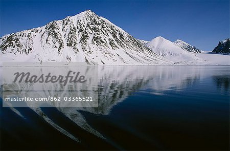 Sillage d'un navire remorqueurs au reflet de la montagne de Magdalenafjorden.