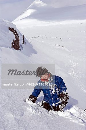 Tromsø, Norwegen Lyngen Alpen. Kleiner Junge hat extrem Fun Rodeln in helle Wintersonne.