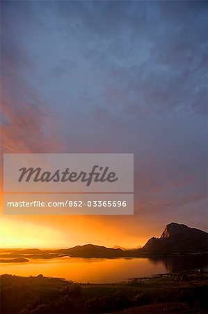 Norway,Nordland,Helgeland. The midnight sun over the islands surrounding the island of Rødøy Island dominated by the 400 metre high peak of Rødøyløva,which translated means 'Lion of Rødøy' and which from a distance also looks like a sphinx