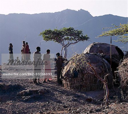 Comme le soleil se lève au-dessus des sommets boisés du Mont Nyiru, membres d'une famille de Turkana discuter et planifient les activités de la journée à l'extérieur de leurs maisons en forme de dôme, qui assurent une protection limitée contre les intempéries.