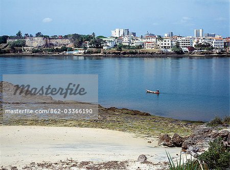 Kenya, côte, Mombasa. Un pêcheur en pirogue de rames de Fort Jésus et la vieille ville de Mombasa. Seulement - les bateaux à voile en bois de la région - les dhows utilisent maintenant le vieux port.