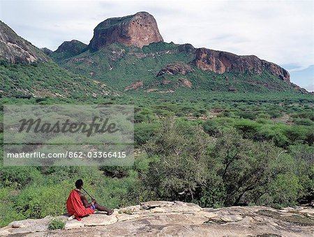 Un guerrier Samburu joue une flûte maison surplombant les Poi, une fonctionnalité de rocher proéminent dans les montagnes de Ndoto de Samburuland.The Samburu du Nord du Kenya sont une communauté pastorale semi-nomadique associée à leurs cousins plus célèbres, la maa parlant des Maasai.