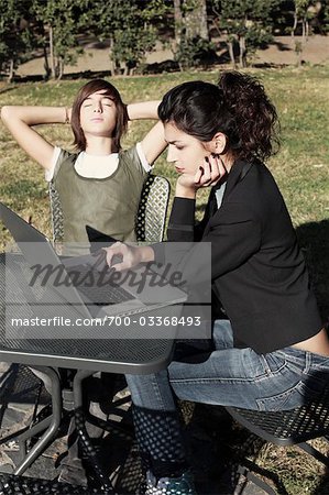 Woman and Boy Sitting Outdoors Using Laptop Computer