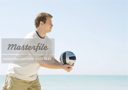 Man serving volleyball on beach