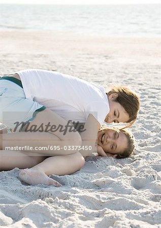 Preteen girls tickling each other in sand