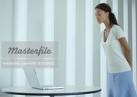 Femme debout, regardant vers le bas pour ordinateur portable