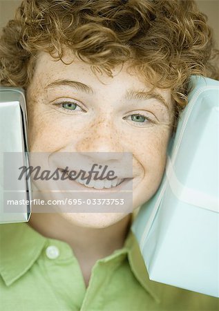 Boy holding up presents on either side of face