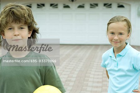 Boy and girl standing in front of driveway, smiling