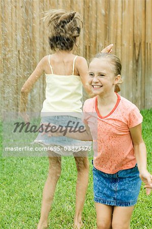 Girls jumping in sprinkler