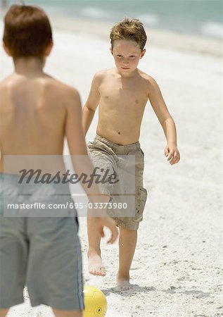 Boys playing with soccer ball on beach