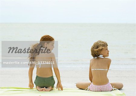 Deux filles, assis sur la serviette de plage, vue arrière