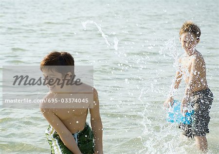 Boys splashing in ocean with buckets