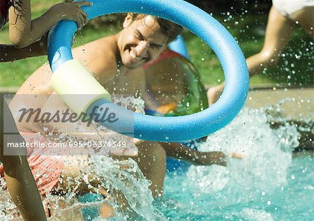 Father and children splashing in swimming pool