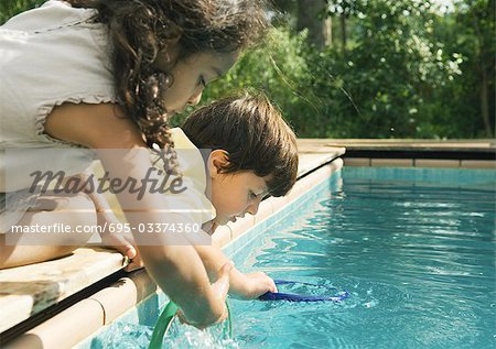 Two children leaning over edge of swimming pool