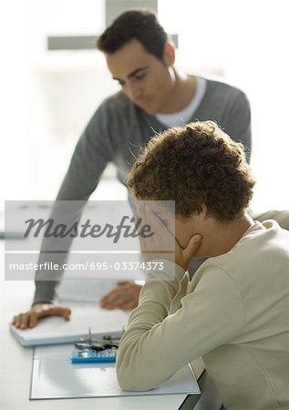 Man helping teenage son with homework