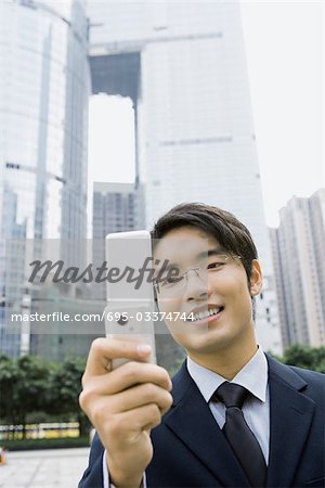 Businessman holding up cell phone, smiling
