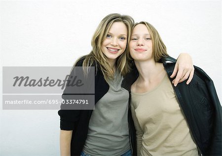 Teenage girls standing side by side, smiling at camera, portrait