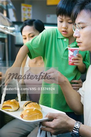 Famille manger fast food, garçon ramasser bun de barre d'état