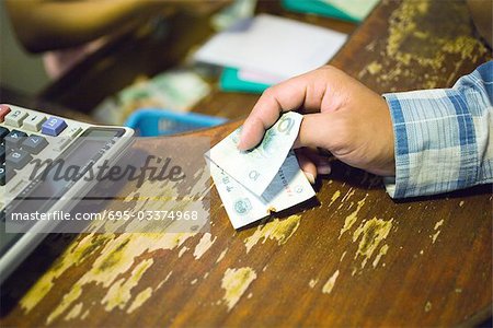 Customer holding out banknote to pay, cropped view