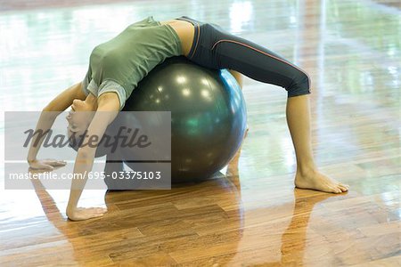 Jeune femme faisant backbend sur boule de remise en forme