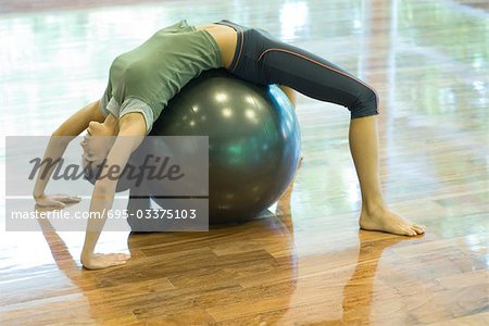 Young woman doing backbend on fitness ball