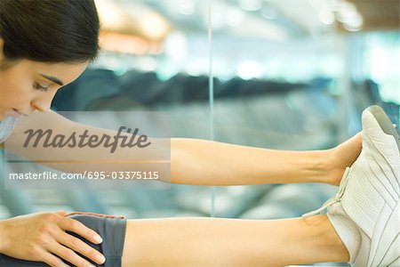 Woman stretching leg on barre