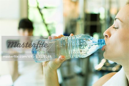 Deux femmes dans la salle de musculation, se concentrent sur la femme au premier plan, bouteille d'eau à boire