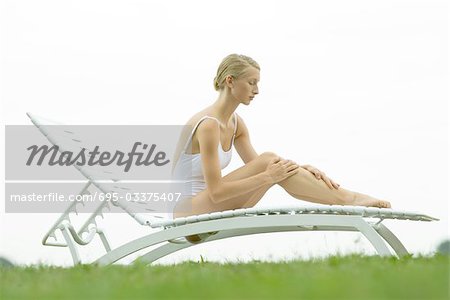 Teenage girl sitting on lounge chair, hands on legs