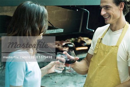 Couple clinking glasses next to barbecue