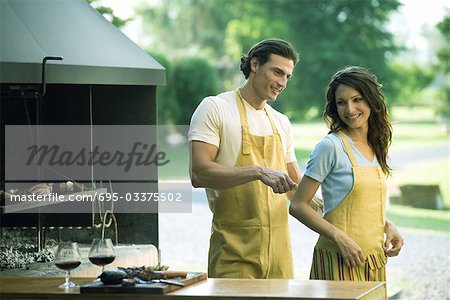Man tying woman's apron by outside wood oven